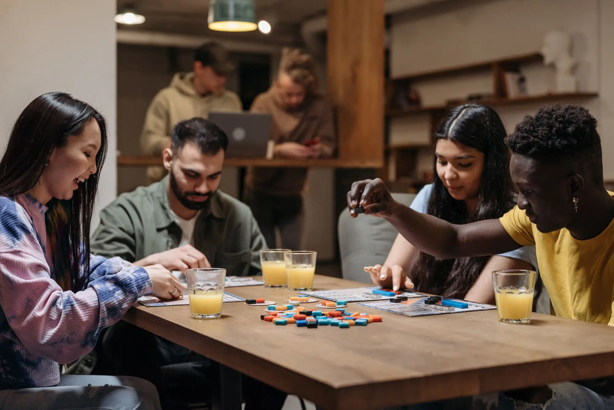 Four friends around a table playing a tile-based board game