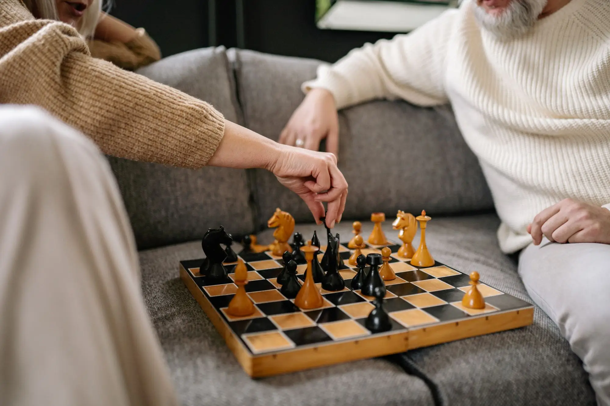 Two people mid-game over a wooden chessboard