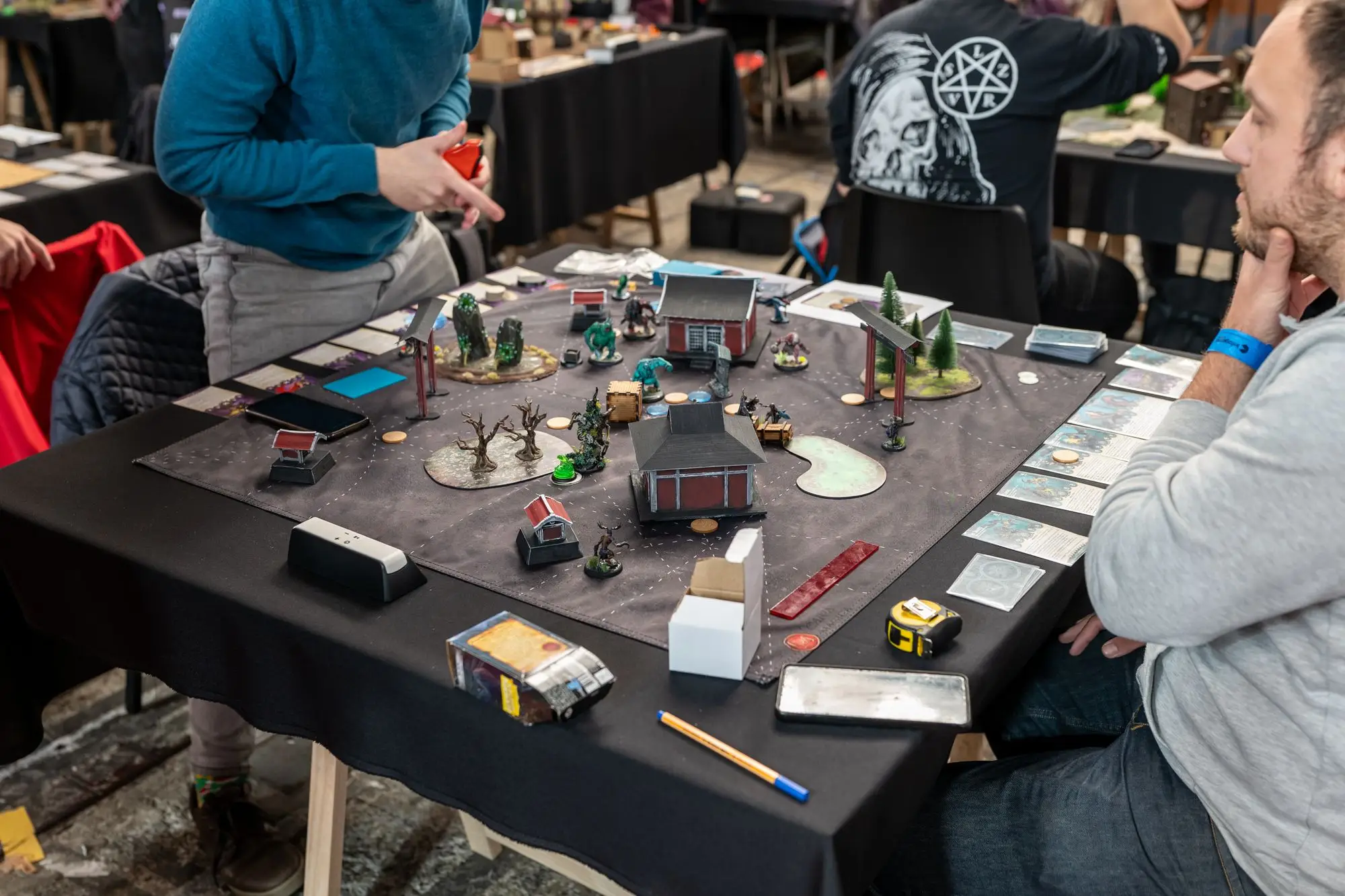 People around a tabletop game with miniatures, terrain and dice