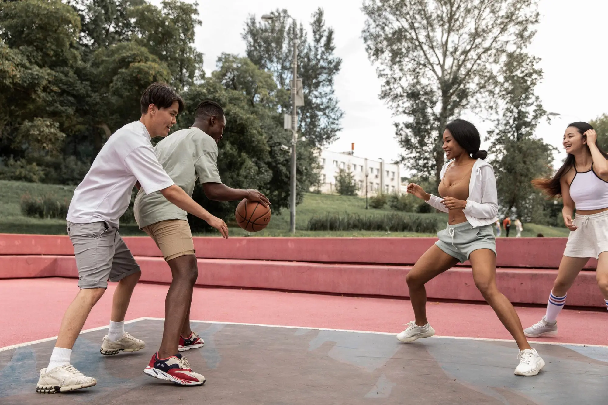 Four friends playing basketball together on an outdoor court