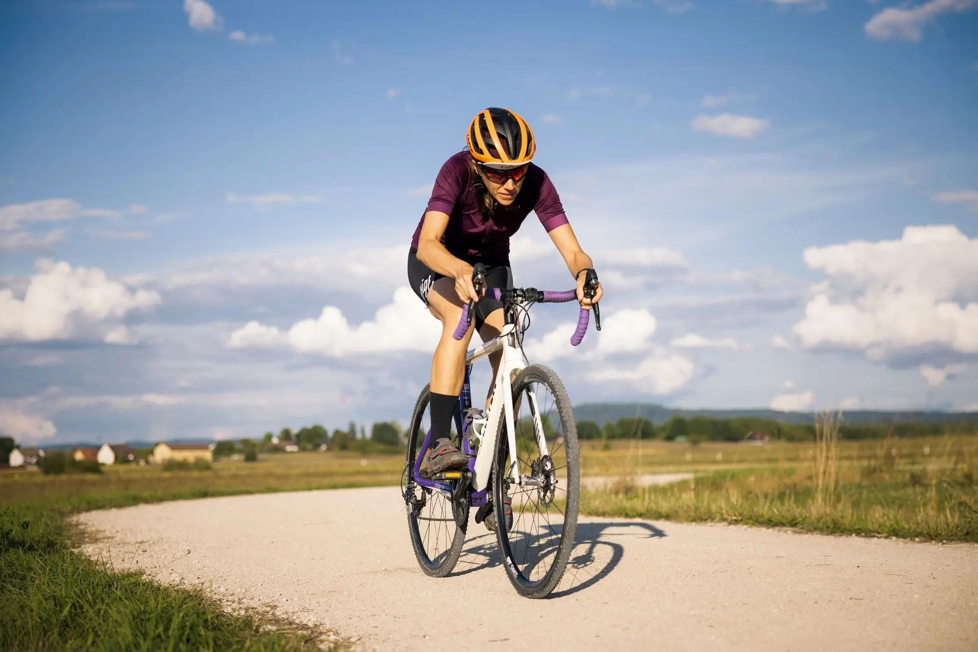 A cyclist on a gravel bike riding a stone track through countryside