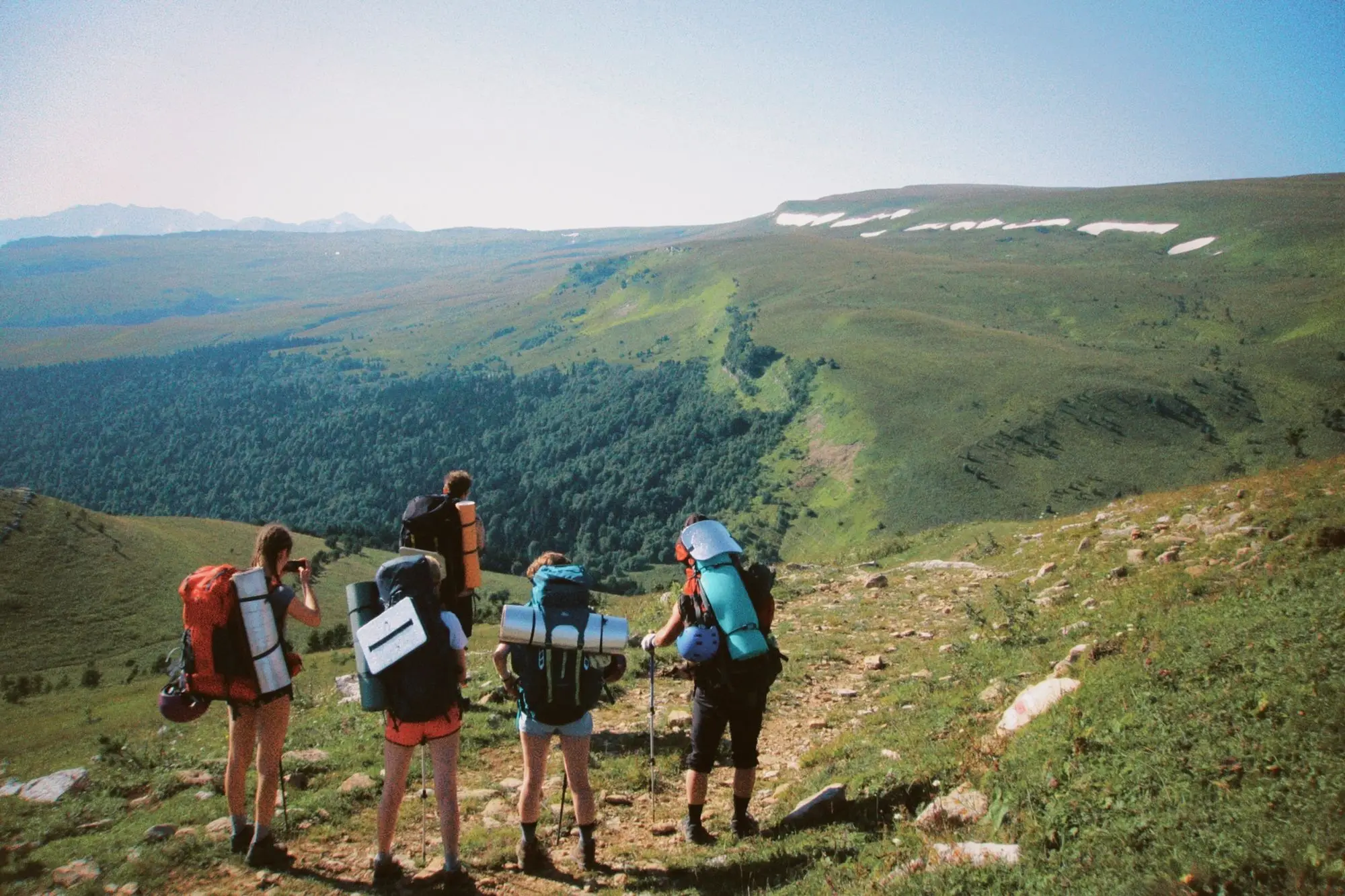 A group of friends walking a ridge together with backpacks