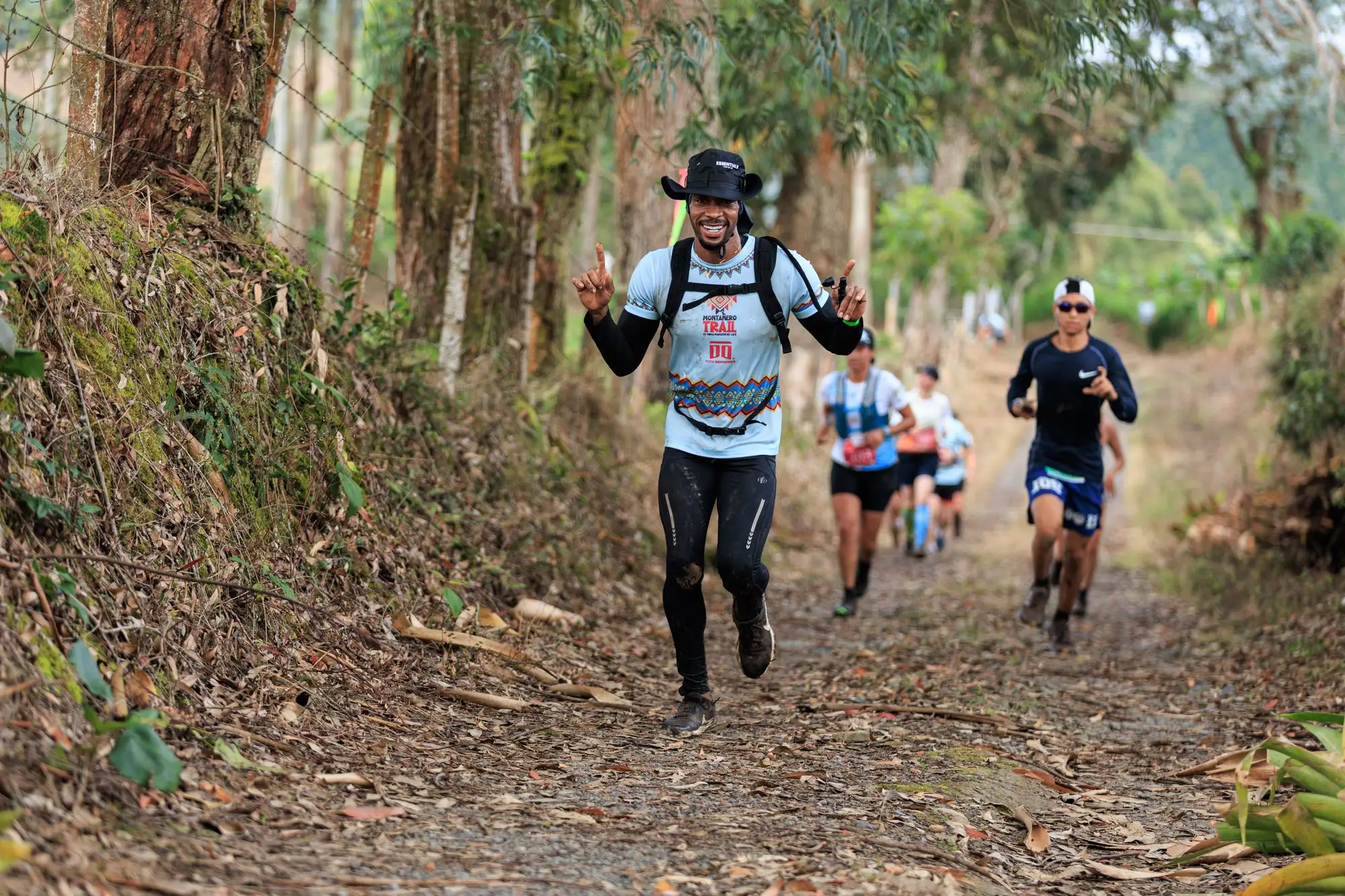 A trail runner celebrating mid-stride on a muddy forest path